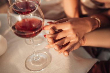 Gelin ve damadın ellerinin yakın çekimi. Genç çiftin bir randevusu var, balayını kutluyorlar, kırmızı şarap içiyorlar, birlikte vakit geçiriyorlar. Nikah yüzüklü karı koca. Aşk konsepti.