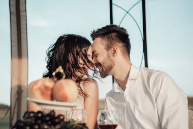 Çadırda servis masasıyla flört eden genç bir çiftin portresi. Yeni evliler balayını kutluyor ve birlikte dışarıda vakit geçiriyorlar. Romantik yemek konsepti.