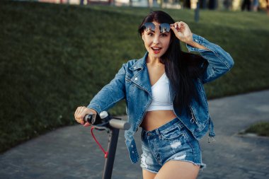 Gülümsemenin portresi, şehrin caddesinde duran elektrikli scooterlı ağzı açık kadının portresi. self-servis sokak taşımacılık kiralama servisi. Kentsel çevre dostu enerji aracı kirala. 