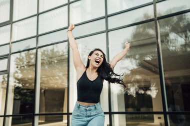 Heyecanlı, mutlu, şehvetli bir kadının çığlığı. Bayan sevinçten kollarını kaldırıyor, yüksek sesle bağırıyor, cübbe ve kot pantolon giyiyor. Kopyalama alanı olan resim. Kutlama konsepti.