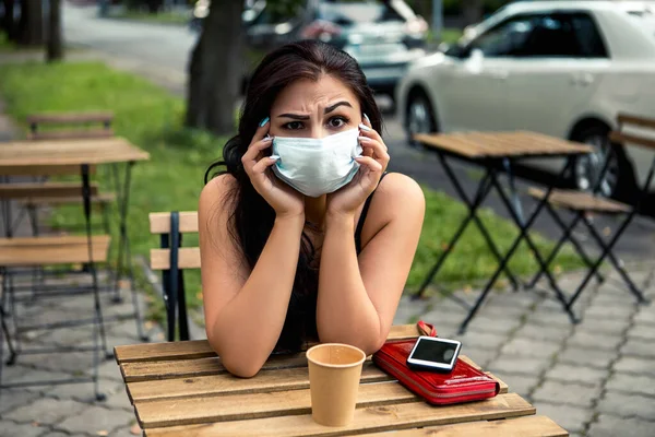 Young upset distressed bad mood woman sitting outside near street cafe or restaurant small business drinking hot coffee beverage. Lovely pretty lady spending time after working day. Healthcare