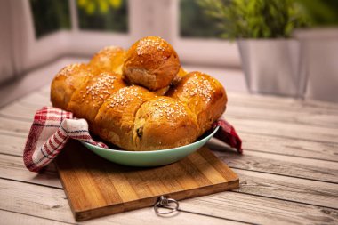 Ev yapımı yemek pişirme konsepti. Taze, yumuşak, yumuşak, zencefilli, altın sarısı, susamlı çörekler, tabak kesme tahtasındaki tatlı çörekleri. Fırın ürünleri, mutfak havlusu, kopyalama alanı.