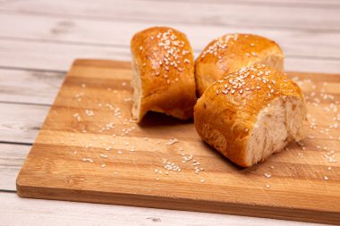 Yan görüş ev yapımı yemek pişirme konsepti. Taze, yumuşak, yumuşak, zencefilli, kahverengi, susamlı çörekler, ekmek dilimleme tahtasındaki tatlı çörekleri. Fırın ürünleri, kopyalama alanı olan resim.