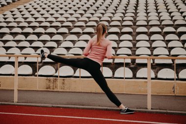 Kız sicimin üzerine oturmadan önce ısınıp ısınıyor. Koşu bandında koşmaya hazırlanan bayan koşucu. Sağlıklı bir yaşam tarzı. Motivasyon kavramı.