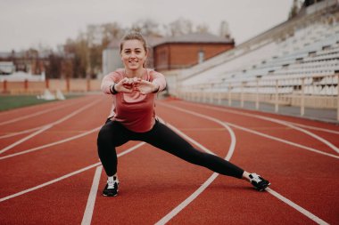 Kızın arkadan görüntüsü geriliyor, vücudunu ve kaslarını verimli bir spor için hazırlıyor. Şehir stadyumunda esnek kadın spor modeli. Kopyalama alanı olan resim.