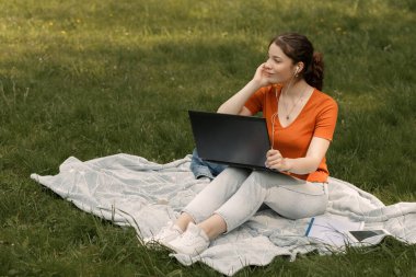 Gülümseyen kız ileriye bakıyor. Milenyum kadını ekose üzerinde dizüstü bilgisayarla çalışıyor. Kadın dışarıda oturuyor ve rüya görüyor. Kopya alanı ile tam boy portresi.