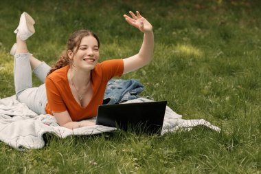 Genç üniversite öğrencisinin hayat tarzı portresi çimlerde yatıp dizüstü bilgisayarla çalışırken arkadaşlarına el sallıyor. Güneşli bir günde şehir parkında ya da avluda fotokopi çeken bir kadın..