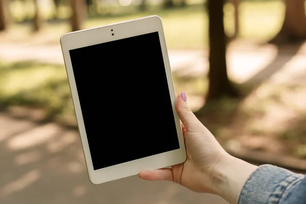 Güneşli bir havada, elinde beyaz tablet olan el bilgisayarı olan bir kadın. Uzayın fotokopisini çekip taklit edin. İnternette resimlerini gösteren bir kadın resmi. Kavram kullanan 5G ağı.