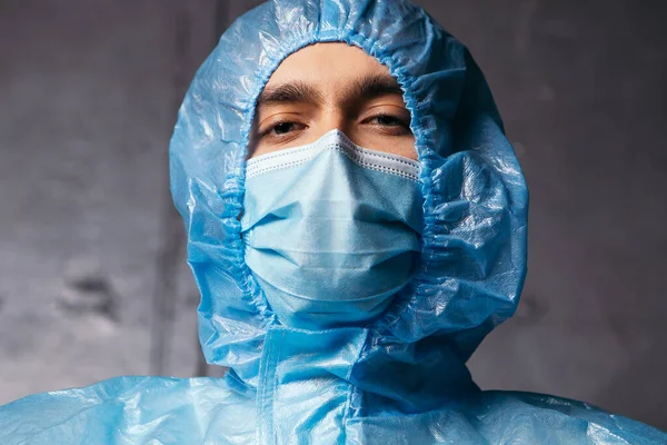 Bottom view doctor medic eyes looking at the camera. Male dressed in protective medical suit and blue face surgical mask. Coronavirus concept. Prevent pendemic disease