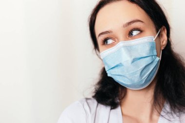 Hemşire genç doktor yana bakıyor. Tıbbi önlük ve cerrahi maske takmış kadın doktor. Kopyalama alanı olan resim. Pandemik virüs koronavirüs konsepti