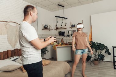 VR kulaklıklı genç bir kadının portresi yaşayanların arasında duruyor ve bir adam onu av köpeğiyle kontrol ediyor. Sanal Gerçeklik gözlüğü kullanan bir çift oyun oynuyor. Kopyalama alanı olan resim.