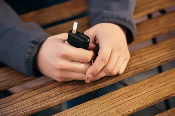 Dışarıda sigara içen genç bir adam var. Elektronik sigara ısıtıcısı. İçinde çubuklar olan duman ve buhar sistemi, fotokopi alanı olan görüntü. Sağlıklı ciğerlere zararlı bir alışkanlık.