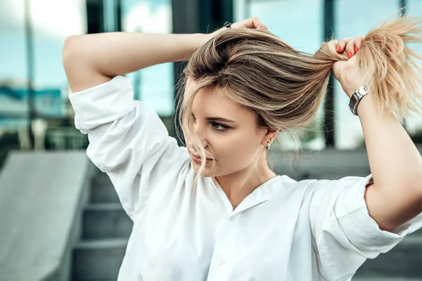 女がコンクリートの階段を離れて見て座っている 白いエレガントなシャツに身を包んだ女性は 髪の毛は コロナウイルスのパンデミックのために隔離中に新しい髪の滑らかな髪の効果を楽しむことができます ファッションコンセプト — ストック写真