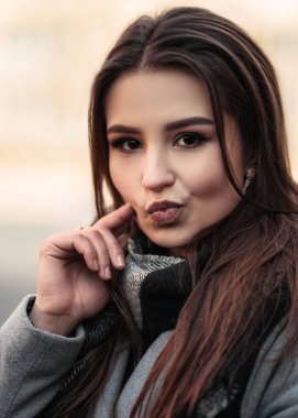 Genç Hintli bir kadının dikey portresi. Sokakta durmuş, komik suratlar yapıyor, yüzünü buruşturuyor, kameraya bakıyor..