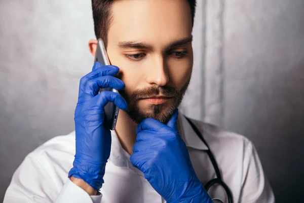 男が話して携帯電話の近代的なガジェットを保持ジェスチャーのように親指を表示します 青いウイルス使い捨てフェイスマスク手袋聴診器首と白いシャツに身を包んだ医師看護師 スペースのコピー — ストック写真