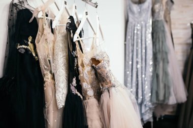 Giyim mağazasının alışveriş merkezindeki bir askıda asılı çeşitli renkte güzel gelinlikler. Moda tarzı bir sergi. Kopyalama alanı olan resim.