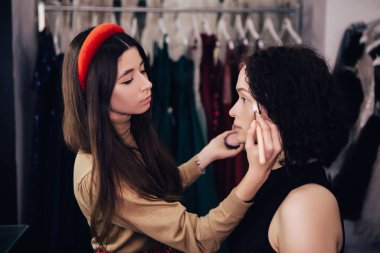 Makyaj sanatçısı makyajını pudra süren bir kadına yapıyor. Makyaj için yüz makyajı için fırça kullanan bir vizör. Güzellik endüstrisi stüdyosu, fotokopi alanı.