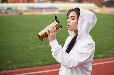 Genç atletik kız koşu bandında spor yaptıktan sonra taze su proteini içiyor. Spor giyimli kadın spor model stadyumu. Boşluğu kopyala