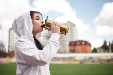Genç atletik kız koşu bandında spor yaptıktan sonra taze su proteini içiyor. Spor giyimli kadın spor model stadyumu. Boşluğu kopyala