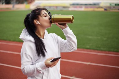 Genç atletik kız koşu bandında spor yaptıktan sonra taze su proteini içiyor. Spor giyimli kadın spor model stadyumu. Boşluğu kopyala