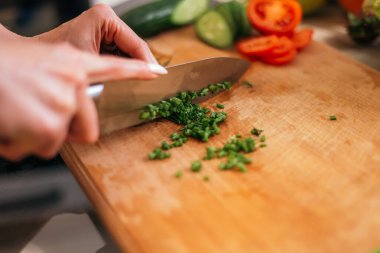 Yakından çekilen kadın yeşil salata, dereotu, meyve ve sebze doğruyor ahşap kesim tahtası. Eğitimden sonra kahvaltı hazırlayan bir kadın, sağlıklı yemekler pişiren bir kadın..