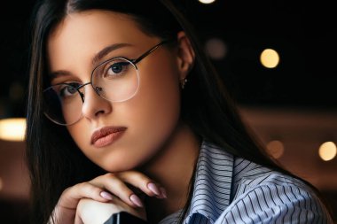 Yakın plan iş kadını, kafede oturan serbest çalışan, öğle yemeği arası veren, akıllı, gözlüklü, gözlüklü, fotokopi odası takan biri. Oldukça sakin bir bayan kameraya bakıyor.