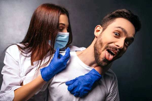 人は咳をする前に口を開けて怖がったワクチンの筋肉内 看護師の医者は病気のウイルスを防ぐために病院で患者をワクチン接種する 女性は青いゴム滅菌手袋を保持注射器を着用 — ストック写真