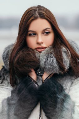 Moda kapanış portresi oldukça kendinden emin bir kadın sokak parkının dışında duruyor moda çevre dostu yapay kürk ceket kışlık giysiler burun delici büyük dudaklar