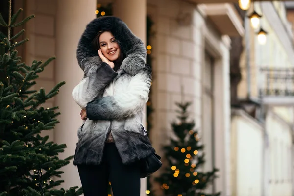 ファッションクローズアップポートレートかなり自信のある女性立ちポーズ外の通りヨーロッパの都市服トレンディーなエコフレンドリーな人工毛皮のコート冬の雪の鼻ピアス顔大きな唇 — ストック写真