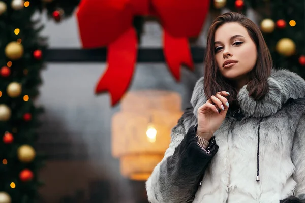 ファッションクローズアップ女性立ちストリートヨーロッパ都市新年の装飾お祝いの休日2022服トレンディーなエコフレンドリーな人工毛皮のコート冬の雪の鼻ピアス顔大きな唇 — ストック写真