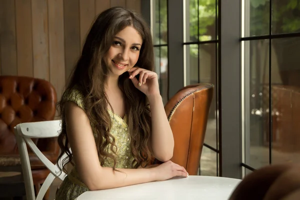 Jolie fille souriant à une table — Photo