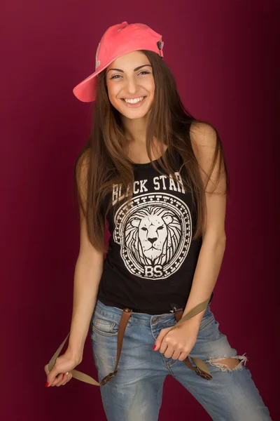 Bella donna dai capelli castani sorridente in un berretto e jeans — Foto Stock