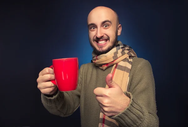 Uomo sorridente che indossa una sciarpa e una tazza in mano — Foto Stock