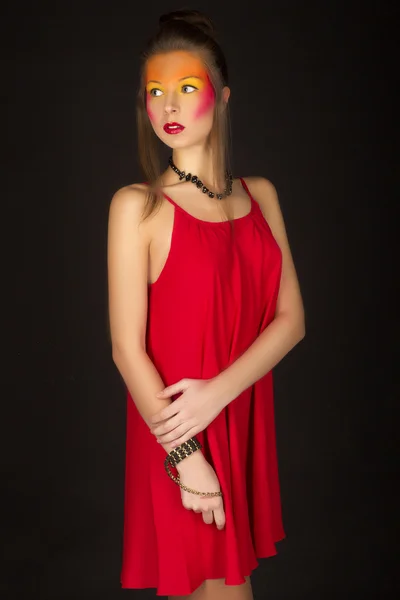 Ragazza in un abito rosso con brillante trucco creativo — Foto Stock