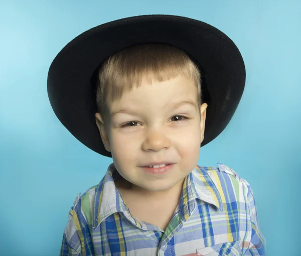 Kleine jongen in een shirt en een zwarte hoed — Stockfoto