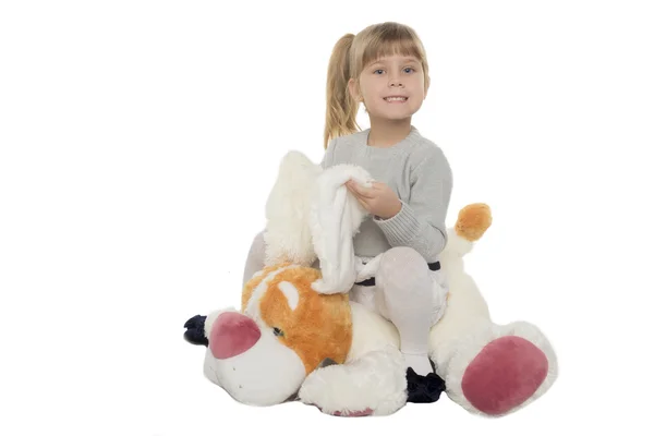 Little girl sits on a toy dog — Stock Photo, Image