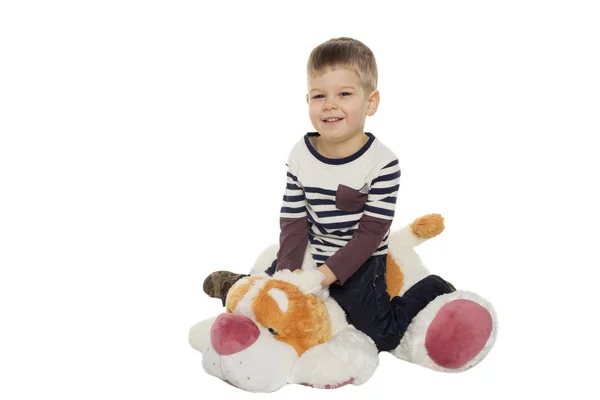 Küçük çocuk bir oyuncak köpek üzerinde oturur — Stok fotoğraf