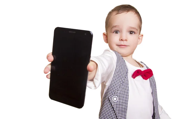 Elegante niño en traje a cuadros y pajarita muestra un móvil — Foto de Stock