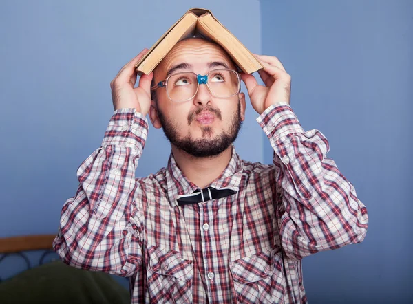 Rolig nörd håller en bok på huvudet — Stockfoto