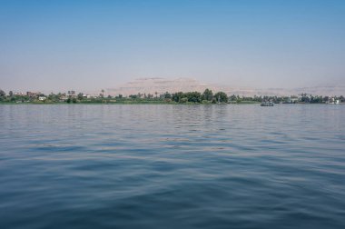 Luxor, Mısır - 27.07.2025. Nil Nehri manzaralı kıyı şeridi boyunca oteller ve binalar ve açık mavi bir gökyüzü.