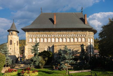 Piatra Neamt, Romanya 16.10.2025. Renkli seramik disklerle Ortaçağ Aziz Yahya Kilisesi (1498) ve Büyük Kule Stephen, Piatra Neamt, Romanya. UNESCO listesindeki Moldova kilisesi, sonbahar güneş ışığı, tarihi mimari