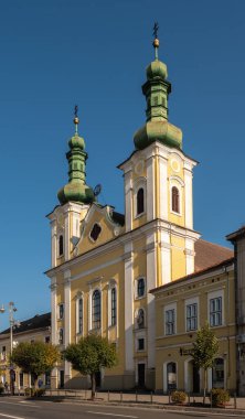 Targu Mures, Romanya - Ekim 17.2025. Aziz Vaftizci Yahya 'nın Roma Katolik Kilisesi' nin beyaz, tarihi kulesi Targu Mures 'te trafik ve ağaçlarla çevrili açık mavi gökyüzüne karşı dimdik ayakta duruyor.