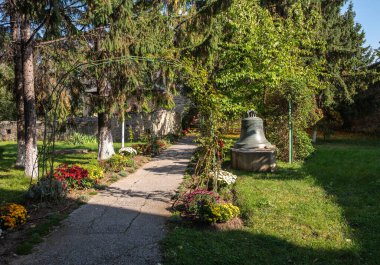Galata Manastırı, Romanya - 23 Ekim. 2025 yılı. Tarihi Galata Manastırı 'nın çimenli, gölgeli avlusunda, üzerinde süslü oymalar bulunan büyük, eski bir bronz çan duruyor.