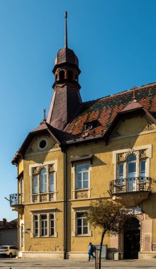 Targu Mures, Romanya - Ekim 17.2025. Romanya 'nın Targu Mures kentinin tarihi merkezinde, parlak mavi gökyüzü altında süslü binalar, sokak parkı, trafik ve sonbahar ağaçlarının yer aldığı bir sokak manzarası