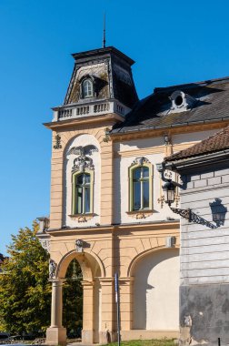 Medya, Romanya - Ekim 20.2025. Romanya 'nın Medias kentinde klasik Sakson mimarisi, kırmızı kiremitli çatılar ve park halindeki arabalarla renkli tarihi cephelerin yer aldığı bir caddenin güneşli perspektifi