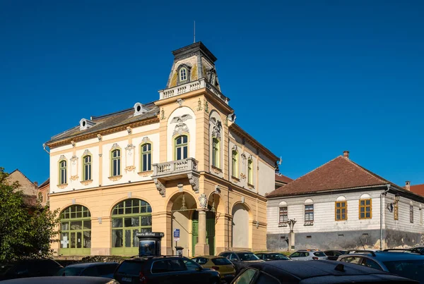 Medya, Romanya - Ekim 20.2025. Romanya 'nın Medias kentinde klasik Sakson mimarisi, kırmızı kiremitli çatılar ve park halindeki arabalarla renkli tarihi cephelerin yer aldığı bir caddenin güneşli perspektifi