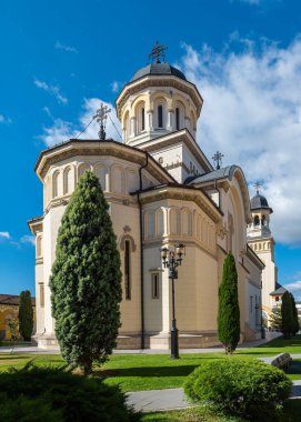 Alba Iulia, Romanya - Ekim 19.2025. Tarihi Ortodoks Taç Giyme Töreni Katedrali 'nde parlak mavi gökyüzünün altında süslü beyaz taş mimari ve karanlık kubbeler yer alıyor.