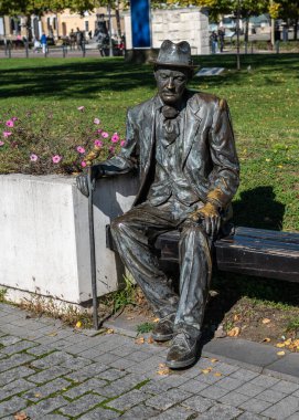 Romanya 'nın Alba Iulia kentinde Ekim 19.2025' te baston ve fötr şapkalı yaşlı bir adamın bronz heykeli Romanya 'nın Alba Iulia kentinin Kalesi' ndeki ahşap bir bankta oturuyor.