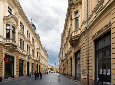 Cluj-Napoca, Romanya - Ekim 18.2025. Cluj-Napoca 'da, Ortodoks Katedrali' nin uzak kubbesine uzanan tarihi mimari süslerle dolu dar bir caddeye zemin düzey bir perspektif.