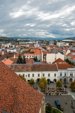 Cluj-Napoca, Romanya - Ekim 18.2025 Romanya 'nın Cluj-Napoca kentinin tarihi merkezi, bulutlu bir gökyüzü altında geleneksel kırmızı başlıklı çatılar, şehir sokakları ve St. Michael Kilisesi' ni gösteriyor.